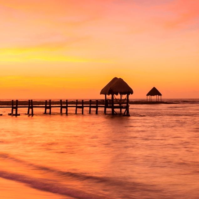 Un muelle en el aterdecer de una playa en cancun